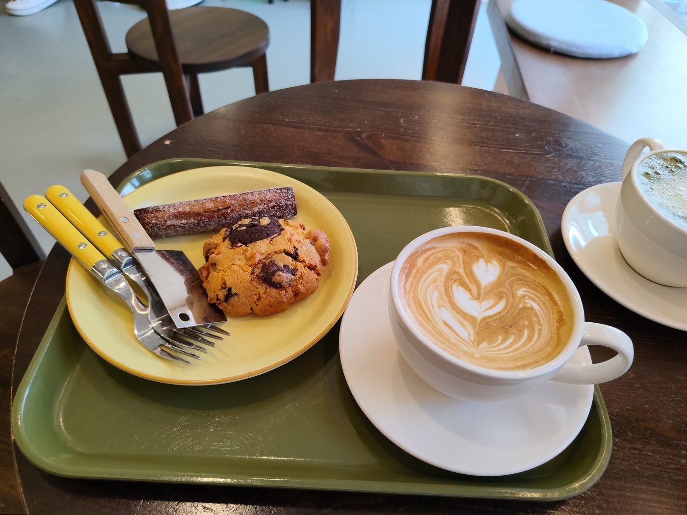 Café-Latte mit feiner Latte-Art auf einem grünen Tablett in einem Café in Korea