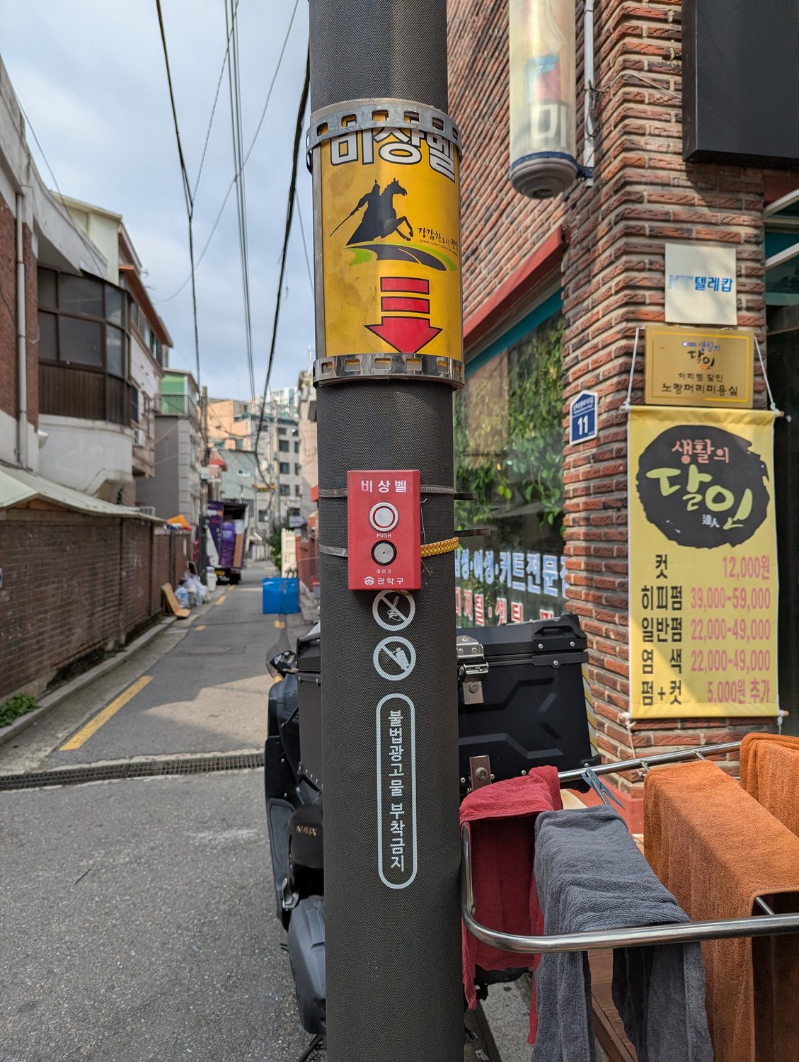 Roter Straßen-Notrufknopf „비상벨“ an einem Laternenmast in einer Seouler Wohngasse